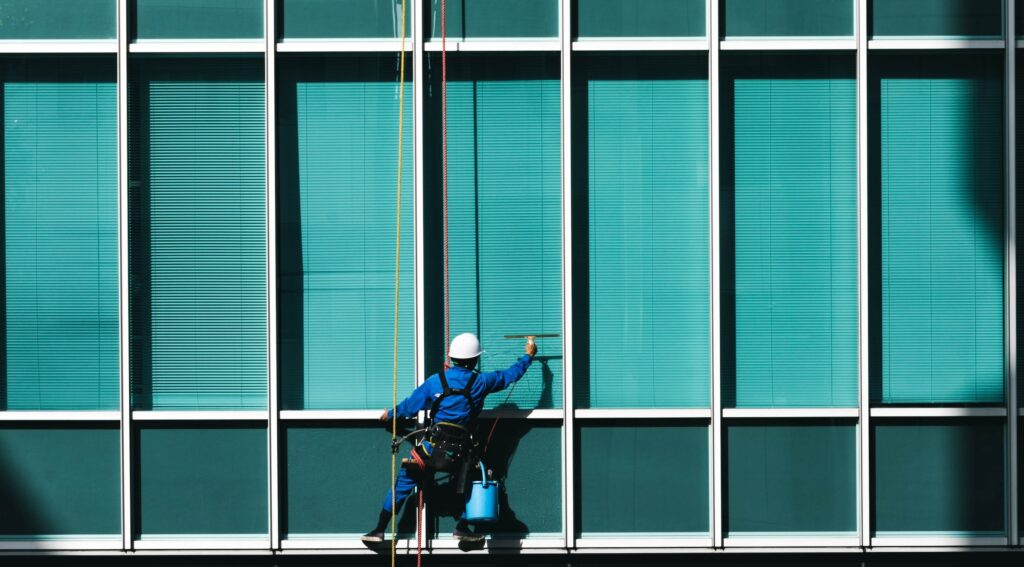 Vinduespudser renser en stor glasfacade på en erhvervsbygning